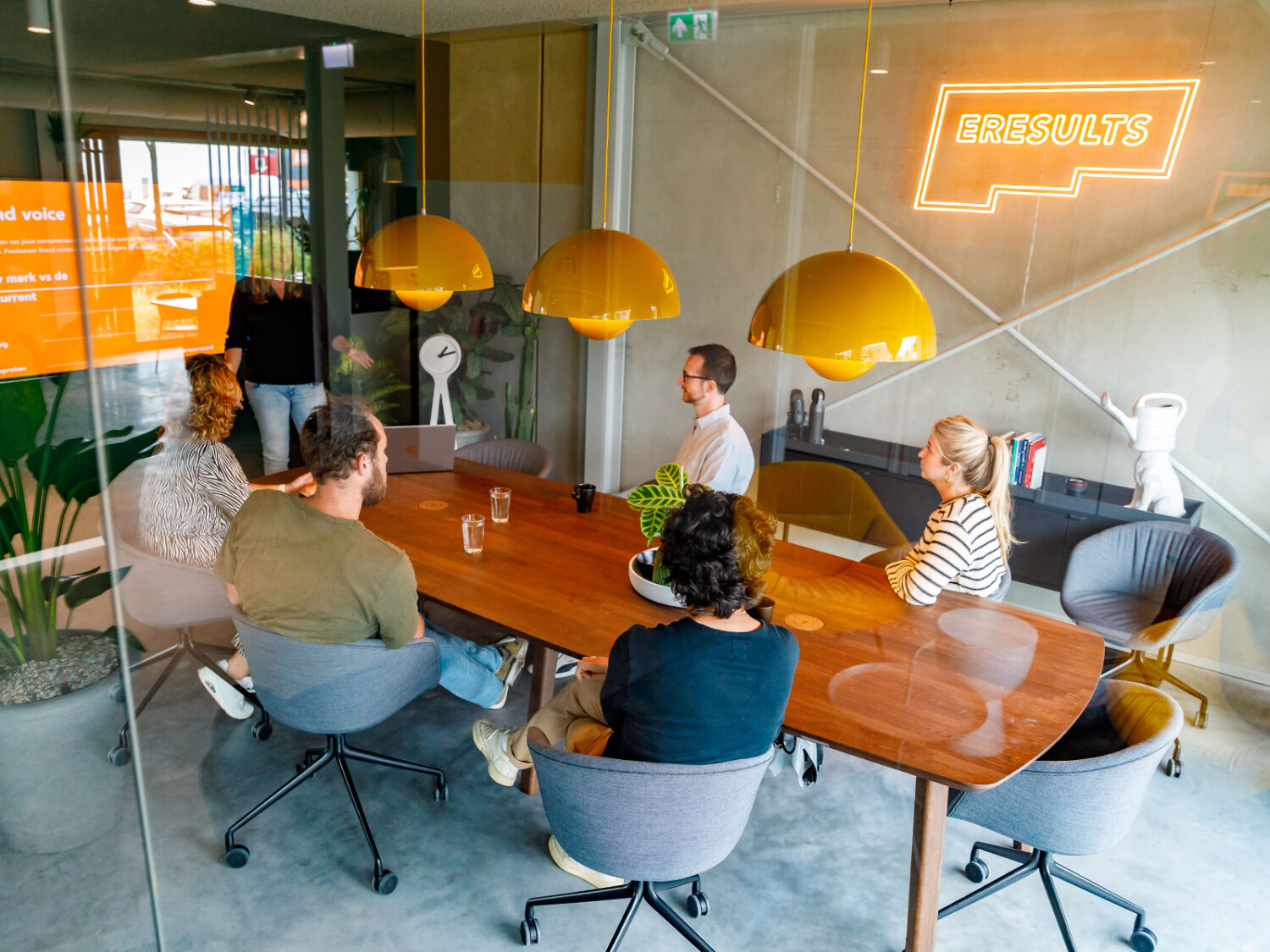 Groep van 5 mensen kijkt in de vergaderkamer naar de presentatie van Marijke